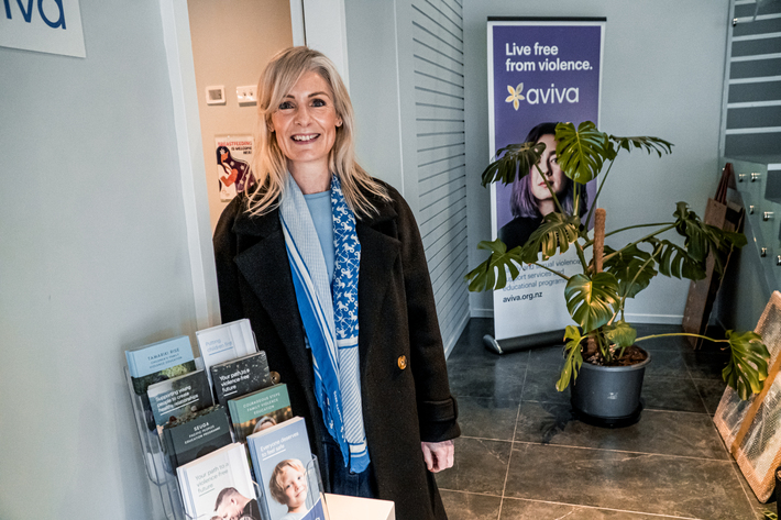 Family Violence Client Services Manager, Katie stands at Aviva reception smiling